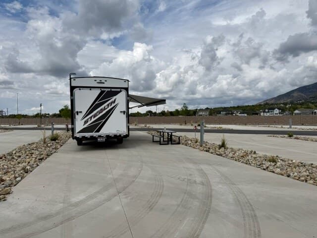 Travel trailer parked on a wide concrete pad with picnic table